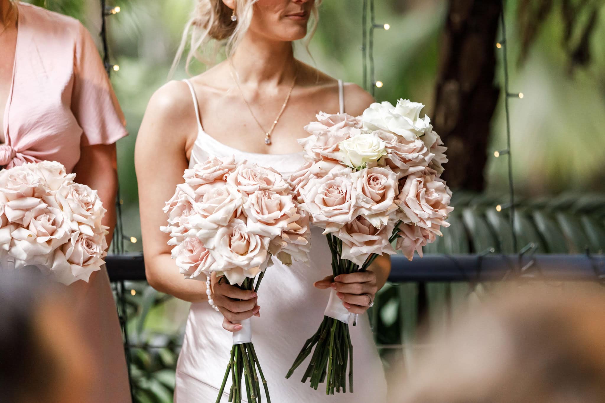 Bridesmaid holding wedding flowers for bride during ceremony.